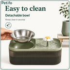 A hand lifting out the detachable stainless steel food bowl from the green pet feeder for fast and easy cleaning.