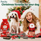 A Christmas scene showing a dog wearing a Santa hat holding a bone toy in its mouth next to a smiling young girl holding a plush Santa toy, with a Christmas tree and a red gift bag in the background.