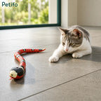 Cute tabby kitten playing with an interactive electronic snake toy on a tiled floor.