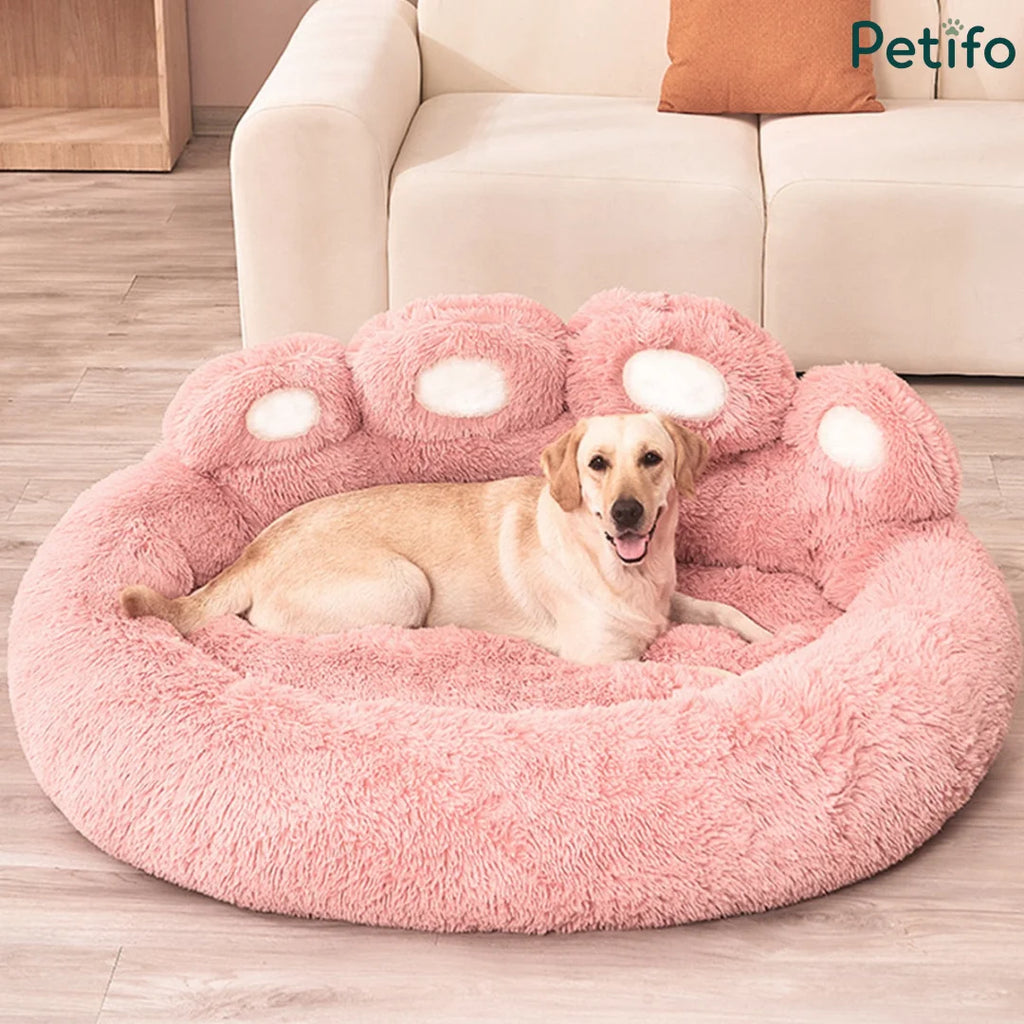 Golden retriever resting inside a soft pink paw-shaped plush dog bed.