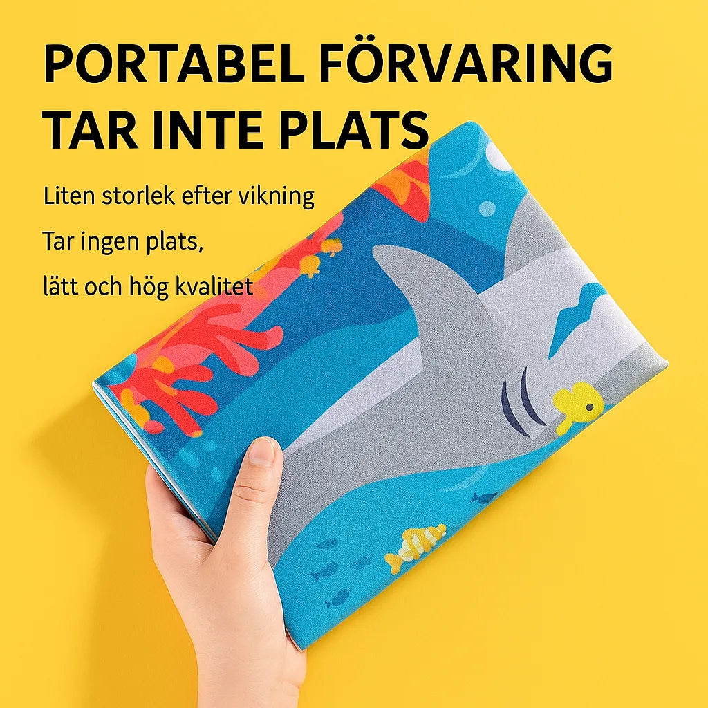 Hand holding a folded water mat with a shark theme against a yellow background – Swedish text shows the product is light, compact and easy to store.